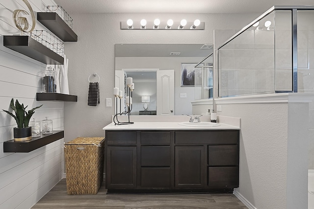 bathroom with wood-type flooring, vanity, and an enclosed shower