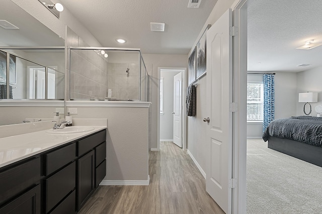 bathroom featuring wood-type flooring, vanity, a textured ceiling, and a shower with shower door