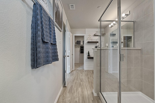 bathroom with hardwood / wood-style floors, a textured ceiling, and an enclosed shower