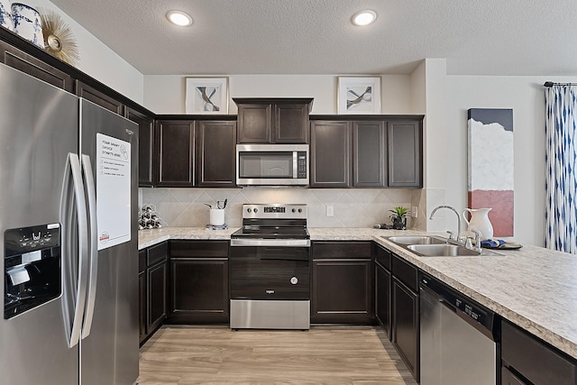 kitchen with decorative backsplash, light wood-type flooring, stainless steel appliances, and sink