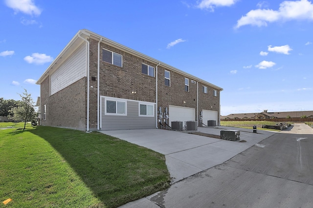 back of property featuring a lawn, central AC, and a garage