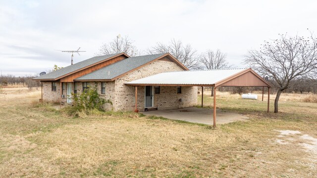 rear view of house featuring a patio, a carport, and a lawn