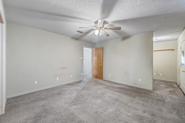 carpeted spare room featuring ceiling fan and a textured ceiling