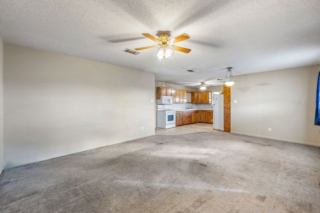 unfurnished living room with ceiling fan, light colored carpet, and a textured ceiling