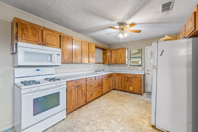 kitchen featuring ceiling fan, white appliances, sink, and a textured ceiling