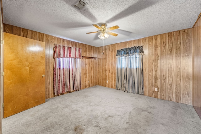 empty room featuring a healthy amount of sunlight, carpet flooring, and wooden walls