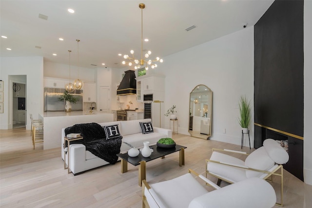 living room with sink, a chandelier, and light wood-type flooring