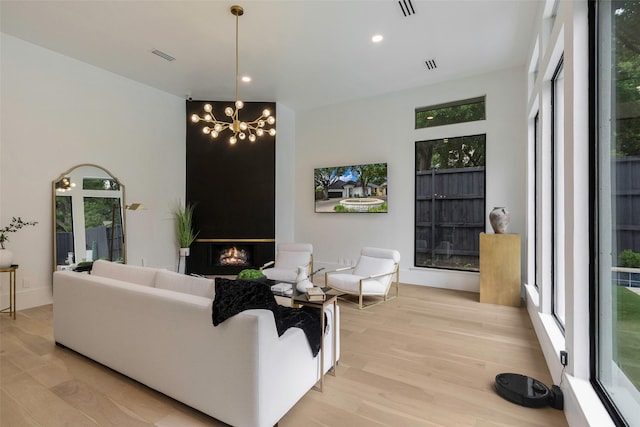 living room with a fireplace, a chandelier, and light wood-type flooring