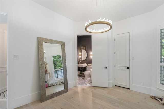 hallway featuring a notable chandelier and light hardwood / wood-style floors