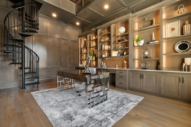 office featuring hardwood / wood-style floors, wooden walls, coffered ceiling, built in desk, and built in shelves