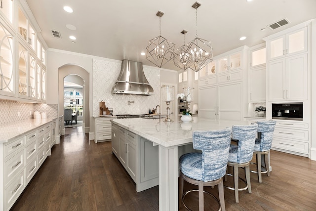 kitchen featuring ventilation hood, a large island, white cabinets, and decorative light fixtures