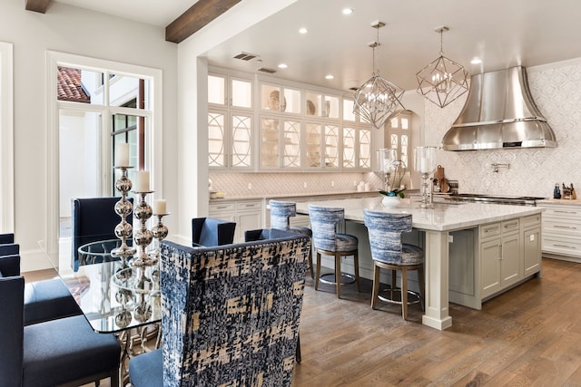 bar with white cabinetry, light stone counters, wood-type flooring, exhaust hood, and beamed ceiling