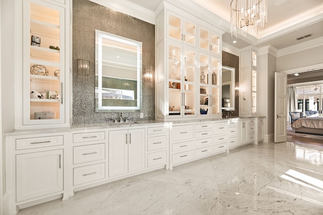 bathroom with crown molding, vanity, decorative backsplash, and a notable chandelier