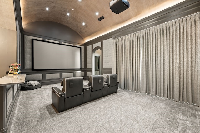 cinema with carpet floors, vaulted ceiling, and brick ceiling