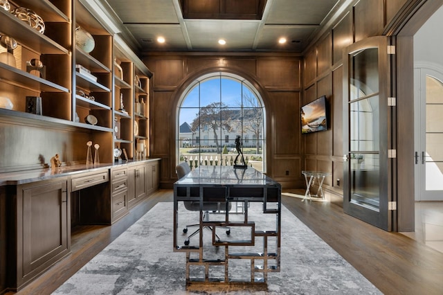 office area featuring dark hardwood / wood-style floors, wooden walls, coffered ceiling, and built in shelves