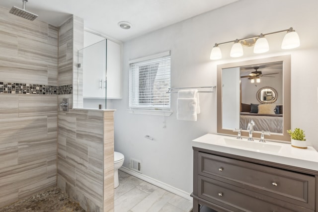 bathroom featuring a tile shower, vanity, toilet, and ceiling fan