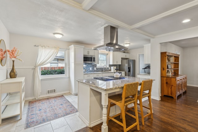 kitchen featuring white cabinetry, sink, a kitchen bar, island range hood, and appliances with stainless steel finishes