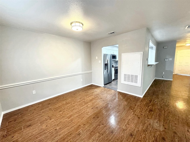 unfurnished room with dark wood-type flooring and a textured ceiling