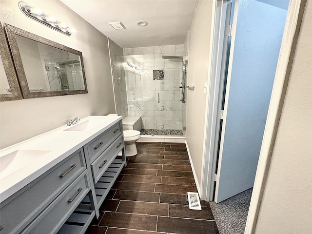 bathroom with vanity, tiled shower, and toilet