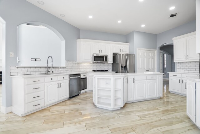 kitchen featuring a kitchen island, a sink, visible vents, white cabinets, and appliances with stainless steel finishes