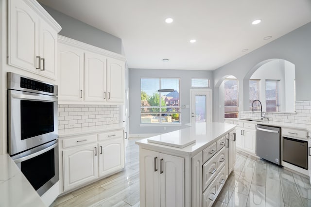 kitchen with a center island, light countertops, appliances with stainless steel finishes, white cabinets, and a sink