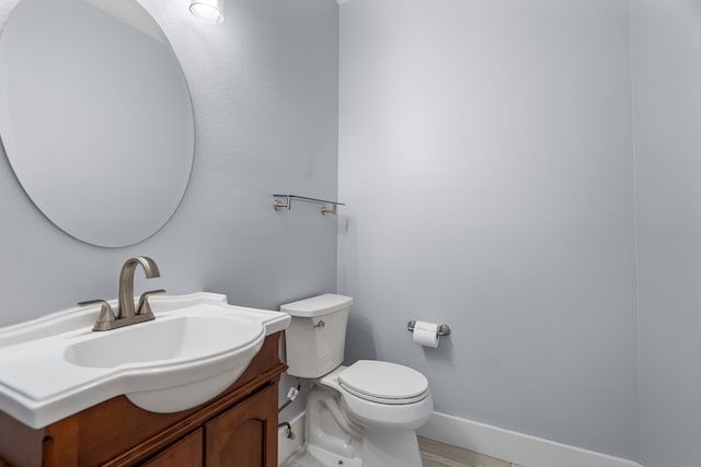 bathroom featuring toilet, baseboards, and vanity