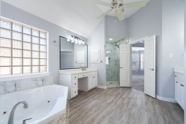 bathroom with lofted ceiling, a whirlpool tub, a marble finish shower, and vanity