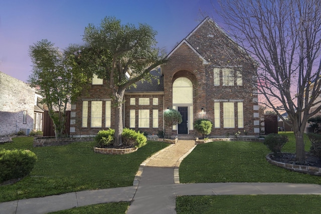 view of front of house featuring a yard and brick siding