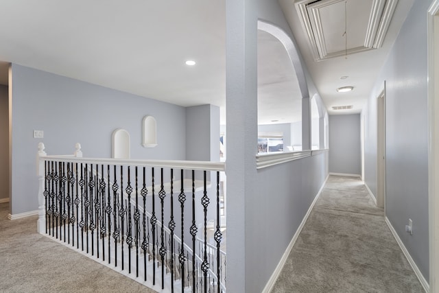 hallway with attic access, carpet flooring, and baseboards