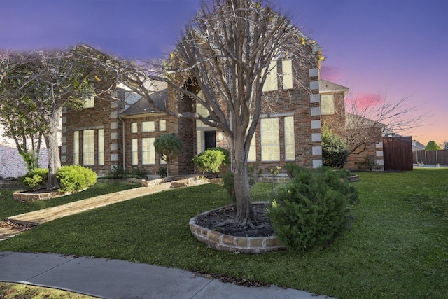 view of front of house with brick siding and a lawn