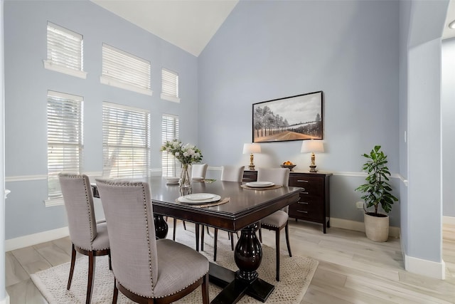 dining space featuring light wood-type flooring and high vaulted ceiling