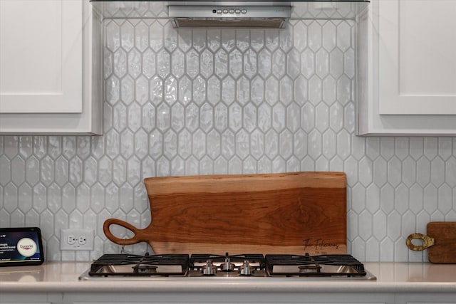 details featuring stainless steel gas cooktop, backsplash, and white cabinets