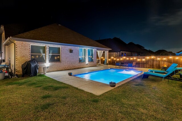 pool at night featuring grilling area and a patio