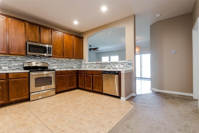 kitchen with ceiling fan, sink, stainless steel appliances, backsplash, and light tile patterned flooring