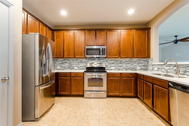 kitchen with ceiling fan, decorative backsplash, sink, and appliances with stainless steel finishes