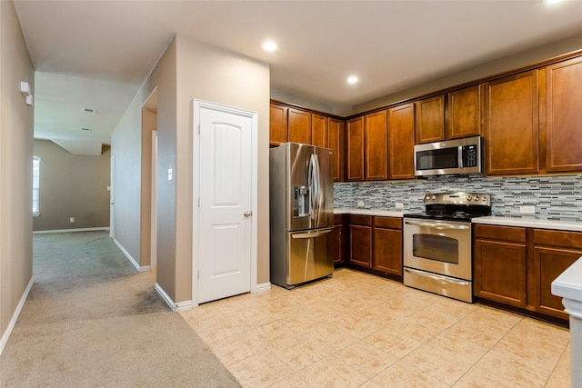 kitchen with decorative backsplash, light carpet, and appliances with stainless steel finishes