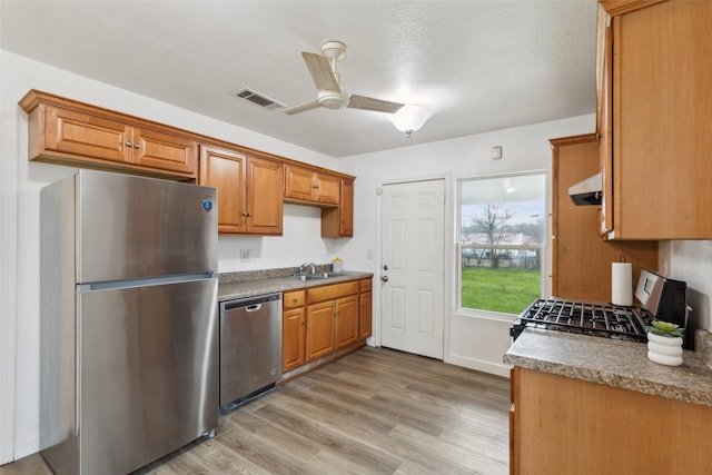 kitchen featuring sink, light hardwood / wood-style flooring, ceiling fan, range hood, and stainless steel appliances