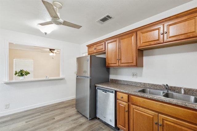 kitchen featuring ceiling fan, appliances with stainless steel finishes, sink, and light wood-type flooring