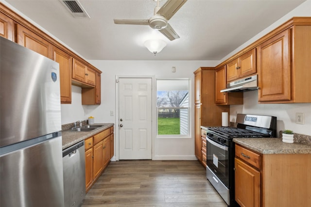 kitchen with appliances with stainless steel finishes, sink, ceiling fan, dark wood-type flooring, and a textured ceiling