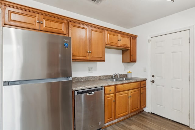 kitchen featuring stainless steel appliances, wood-type flooring, and sink