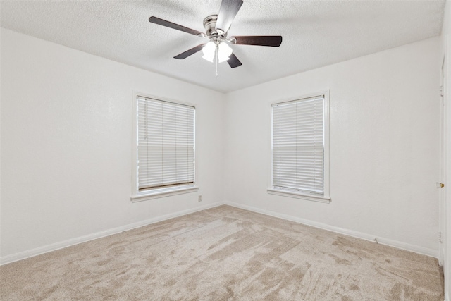 spare room featuring ceiling fan, light carpet, and a textured ceiling