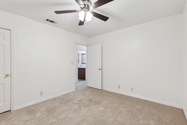 empty room with ceiling fan, light carpet, and a textured ceiling