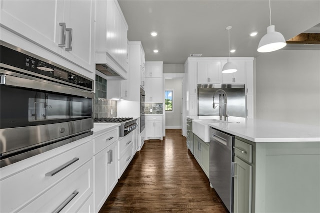 kitchen with appliances with stainless steel finishes, sink, white cabinets, backsplash, and hanging light fixtures