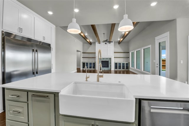 kitchen featuring appliances with stainless steel finishes, decorative light fixtures, a center island, and sink