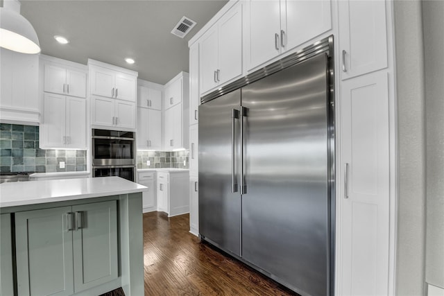 kitchen with white cabinetry, tasteful backsplash, decorative light fixtures, dark hardwood / wood-style flooring, and stainless steel appliances