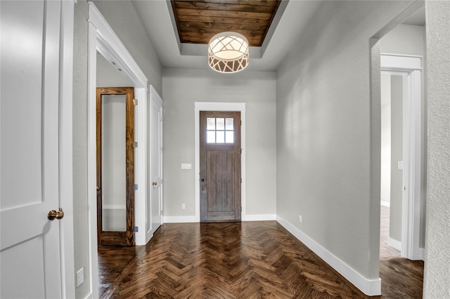 foyer entrance with dark parquet floors and a raised ceiling