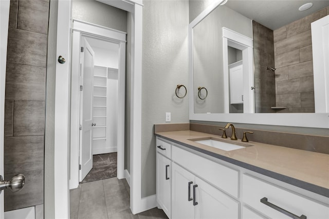 bathroom featuring vanity, tile patterned flooring, and tiled shower