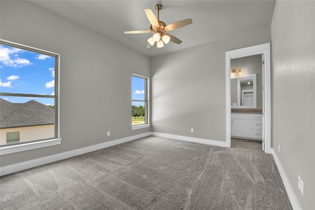 unfurnished bedroom with ceiling fan, ensuite bath, and carpet flooring