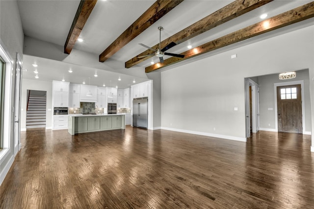 unfurnished living room with beamed ceiling, dark hardwood / wood-style floors, and ceiling fan