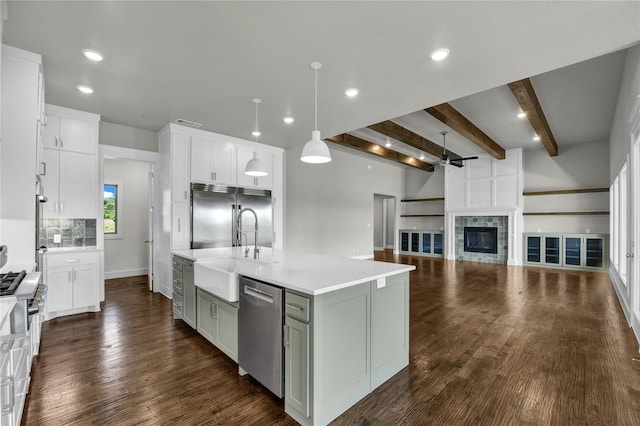 kitchen with decorative light fixtures, dark hardwood / wood-style floors, ceiling fan, stainless steel appliances, and a kitchen island with sink